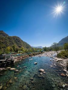 a river with rocks and the sun in the sky at Peace Forest Retreat in Gopeshwar