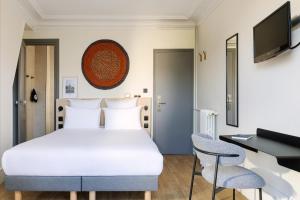ein Schlafzimmer mit Bett, Schreibtisch und Fernseher in der Unterkunft Korner République in Paris