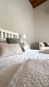 a white bedroom with a large bed and a lamp at Casa das Castanhas - Cinfães, Viseu in Cinfães