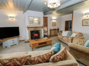 a living room with couches and a tv and a fireplace at Barley Cote Farm in Keighley