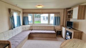 a living room with a couch and a tv at Bella Family Getaway, Church Farm in Pagham