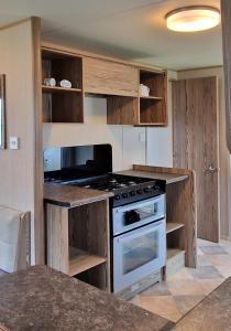 a kitchen with wooden cabinets and a stove top oven at Bella Family Getaway, Church Farm in Pagham