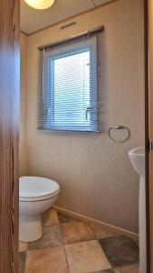 a bathroom with a toilet and a sink and a window at Bella Family Getaway, Church Farm in Pagham