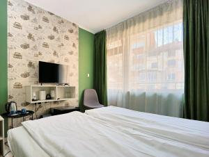 a bedroom with a white bed and a window at Hotel Leda in Sofia