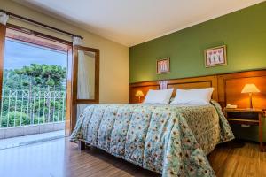a bedroom with a bed and a large window at Pousada Vilage Inn Campos do Jordão in Campos do Jordão