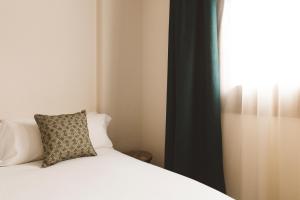 a bedroom with a bed with a pillow and a window at Honest Granada Apartments in Granada