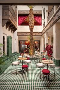 a restaurant with tables and chairs and a palm tree at Riad Dar des Arts in Marrakesh