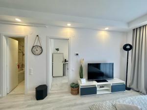 a white living room with a tv and a clock at Anturium Studio #Otopeni #freePool in Tunari