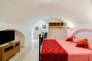 a bedroom with a bed and a flat screen tv at Piazzetta San Giovanni Specchia in Specchia