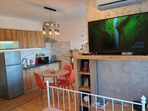 a kitchen with a table and a television on a wall at Apartman Cvijetić in Subotica