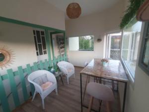 a dining room with a table and white chairs at La Tulipe Périgourdine in Le Buisson de Cadouin