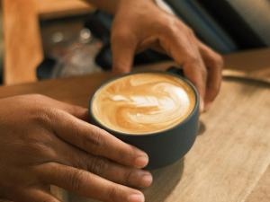 a person holding a cup of coffee on a table at Copacabana Siargao Boutique Hotel & Artcafé in General Luna