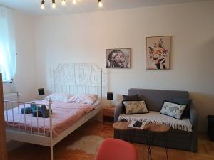 a bedroom with a bed and a couch at Apartman Cvijetić in Subotica