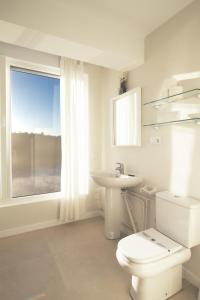 a bathroom with a toilet and a sink and a window at Luaña Beach House in Cóbreces