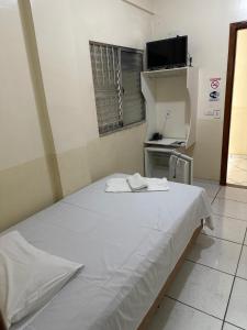 a room with a white bed in a room at Hotel Realeza in Goiânia