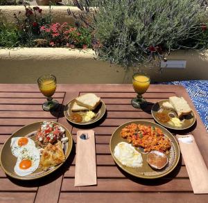 a wooden table with plates of breakfast food on it at Alizea Villas & Suites in Fira