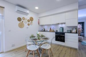 a kitchen with a glass table and white cabinets at Nono Guest House in Ribeira Grande