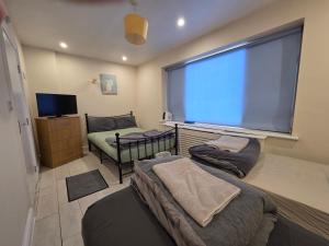 a room with three beds and a large window at Romford Lodge in Romford