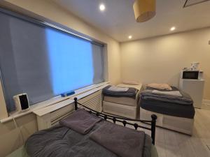 two beds in a room with a large window at Romford Lodge in Romford