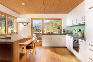 a kitchen with white cabinets and a wooden table at Appartements Veronika in Silbertal