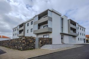 a white apartment building with a stone wall at Nono Guest House in Ribeira Grande