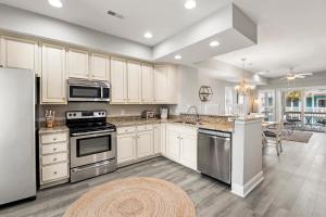 a kitchen with white cabinets and stainless steel appliances at Just Peachy VillageOBX in Kill Devil Hills