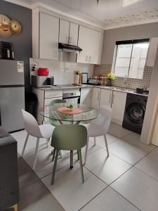 a small kitchen with a glass table and chairs at SinoVilla397 in Pretoria