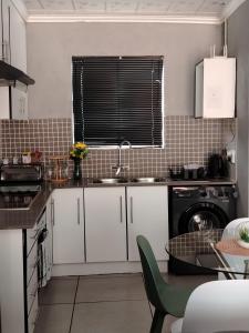 a kitchen with white cabinets and a sink and a dishwasher at SinoVilla397 in Pretoria +5 photos
