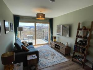 a living room with a couch and a large window at Cadderlie Cabin - Luxury Woodland Escape with Hot Tub Near Oban in Oban