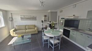 a kitchen and living room with a table and a couch at Gîte le Doux Galet in Bretteville