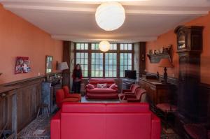 a living room with a red couch and chairs at Manoir de Pincelu in La Courbe