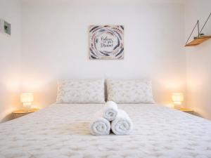 a bedroom with a white bed with towels on it at Le Spacieux à Saint-Omer - 2 chambres, centre et gare à pied, parking privé gratuit in Saint-Omer