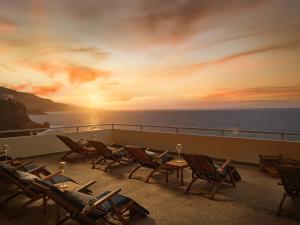 ein Balkon mit Stühlen und ein Sonnenuntergang über dem Meer in der Unterkunft Precise Resort Tenerife in Puerto de la Cruz