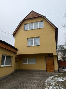 a large yellow house with a brick driveway at Власний будинок in Rakhiv