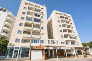 a tall white apartment building on a street at Mackenzie Beachfront Panorama in Larnaca
