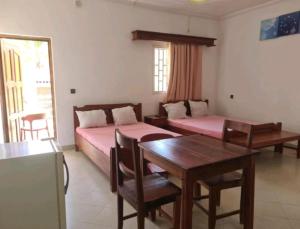 a room with two beds and a table and a dining room at Annexe RAOOF HOTEL in Mahajanga