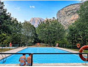 people standing around a swimming pool in front of a mountain at Apartamento Maladeta in Torla-Ordesa