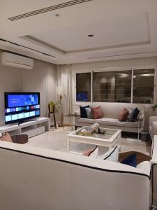 ein Wohnzimmer mit weißen Möbeln und einem Flachbildfernseher in der Unterkunft دور ارضي كبير وواسع للضيافة والتحويل لحسابي بعد الوصول للمنزل in Riad