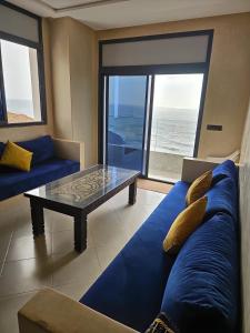 a living room with a blue couch and a glass table at Amouage résidence 3 in Sidi Ifni