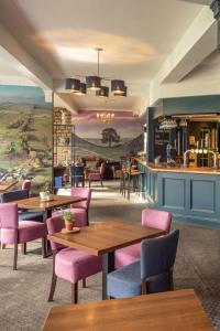 ein Restaurant mit Holztischen und rosa Stühlen in der Unterkunft George Hotel in Hexham