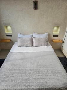 a white bed with two pillows in a bedroom at Amouage résidence 3 in Sidi Ifni