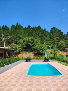 a swimming pool with two umbrellas on top of it at Chalé do Mamute in Atibaia