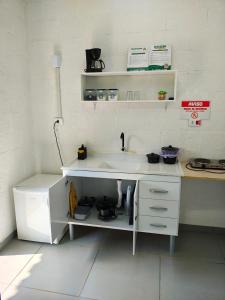 a white kitchen with a sink and shelves at Chalé do Mamute in Atibaia