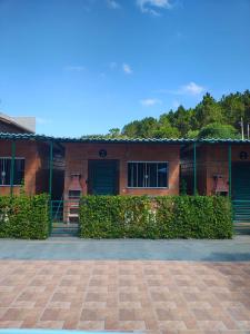 a red brick building with green doors and bushes at Chalé do Mamute in Atibaia
