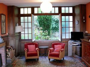 a living room with two chairs and a window at Manoir de Pincelu in La Courbe