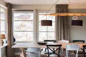 a dining room with a table and chairs and windows at Luxe Duinvilla Stern met sauna voor 8 personen nabij strand en dorp Nes in Buren