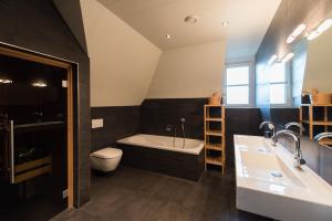 a bathroom with a tub and a toilet and a sink at Luxe Duinvilla Stern met sauna voor 8 personen nabij strand en dorp Nes in Buren +25 photos