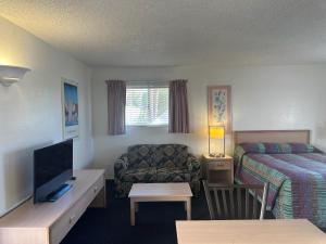 a hotel room with a bed and a couch and a tv at Flamingo Suites in Tucson