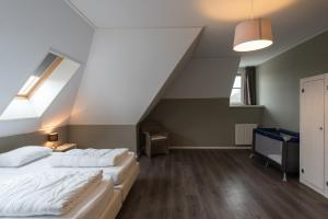 a attic bedroom with two beds and a window at Luxe Duinvilla Stern met sauna voor 8 personen nabij strand en dorp Nes in Buren