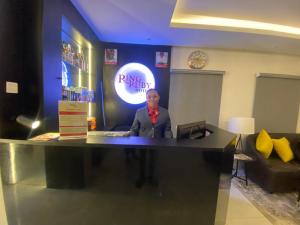 Ein Mann steht an einem Schreibtisch in einem Zimmer. in der Unterkunft Ringruby Hotel, Oladipo Bateye in Lagos